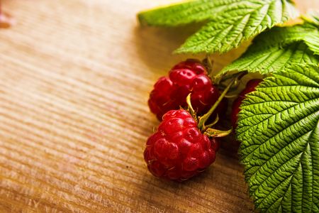 Raspberry fruit with stem and leaves on wooden backgroundの写真素材