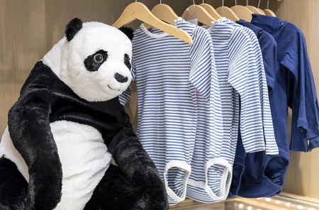 Soft toy panda bear on the background of children's clothing.の写真素材
