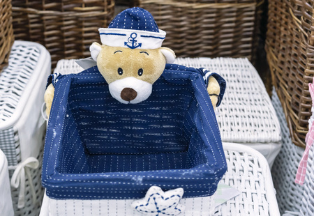 Wicker laundry basket with a teddy bear in marine uniform.の写真素材