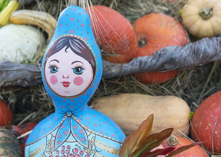 Russian national doll on the background of pumpkins.
