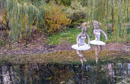 Surreal figures of ballerinas on the lake in a city park.の写真素材
