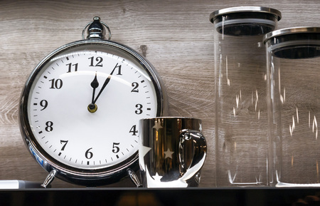 Alarm clock with mug and glass jars on a wooden background.の写真素材