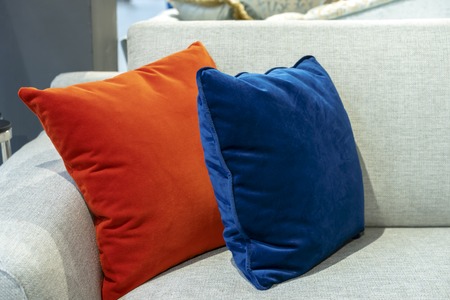 Orange and blue decorative pillows on a beige sofa.の写真素材