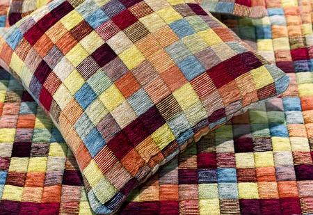 Decorative pillow and plaid are sewn from multi-colored pieces of fabric.