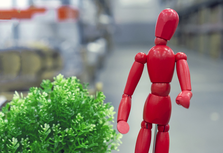Red wooden doll Gestalta next to a green plant.の写真素材