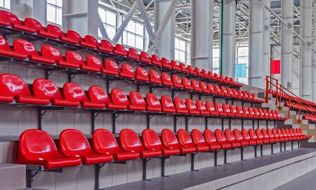 Red plastic seats in the stadium. Tribune fans. Seats for spectators in the stadium.