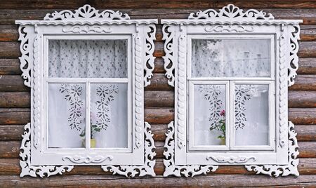 Windows with white carved frames in the old wooden house.の写真素材