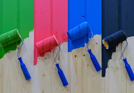 Paint rollers on a wooden wall. Multicolored paint rollers.の写真素材