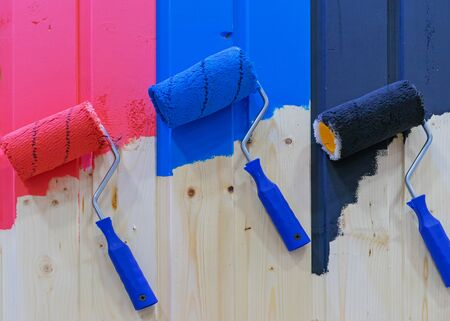 Paint rollers on a wooden wall. Multicolored paint rollers.の写真素材
