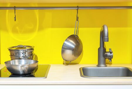 Kid's kitchen with washing, stove and utensils on a yellow background.の写真素材