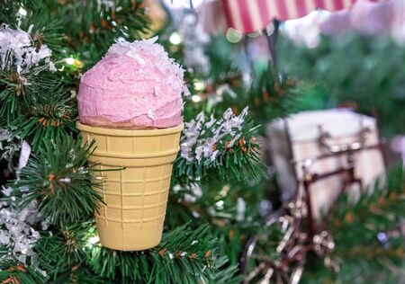Pink ice cream in a waffle cup on a Christmas tree. Christmas decor with ice cream.
