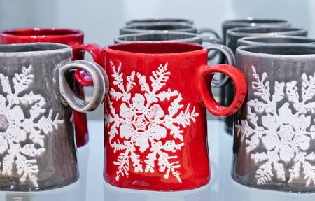Red ceramic mug with a snowflake. Mugs on a store counter.の写真素材