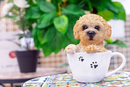 Ceramic figurine of a little puppy sitting in a white cup.の写真素材