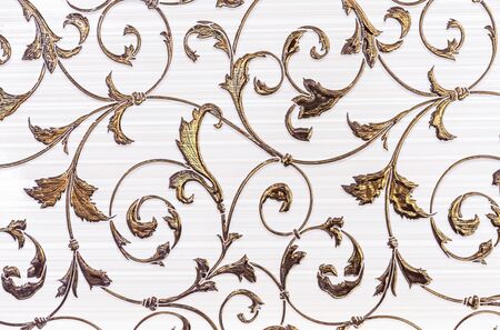 White porcelain tiles with a gold floral ornament. Ceramic tiles with volumetric golden pattern.の写真素材