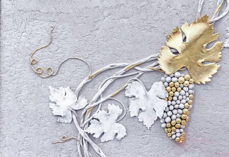 Decorative vine with leaves and bunches of grapes on a background of gray concrete wall.の写真素材