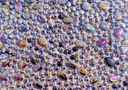 Glossy pebble tiles with rainbow shimmer. Decorative panel made of smooth stones.の写真素材