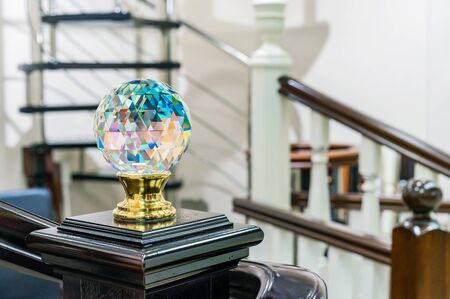 Faceted glass ball with multi-colored highlights is mounted on a wooden staircase.の写真素材