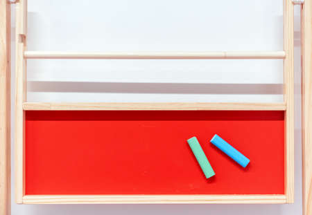Red chalk board with colored crayons for writing and drawing.