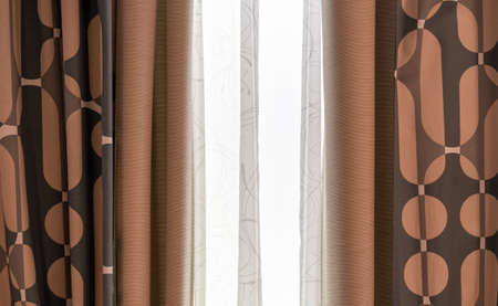 Brown patterned curtains and white tulle on the living room window.の写真素材