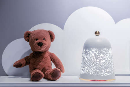 Brown teddy bear and openwork lamp in the interior of the children's room.の写真素材