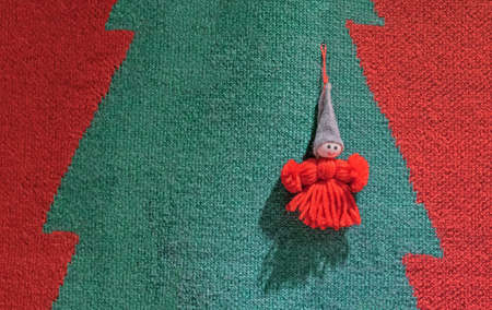 Doll made of red yarn with a felt cap on a woolen background.の写真素材
