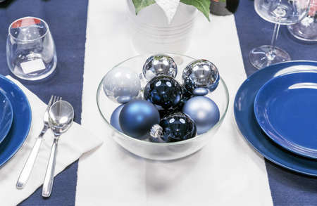 Dark blue and white Christmas balls in a transparent glass vase on a holiday table.の写真素材