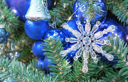 Glass Christmas snowflake on the background of dark blue Christmas balls.