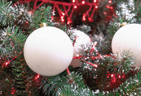 White Christmas balls with a red garland on the Christmas tree.の写真素材