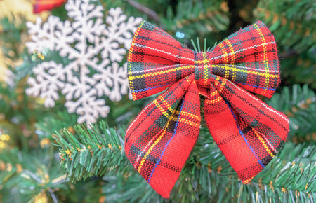 Red bow with a scottish cage and a white snowflake on the Christmas tree.の写真素材