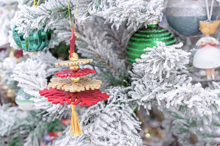 Multicolored snowflakes with gold beads on a snow-covered Christmas tree.の写真素材