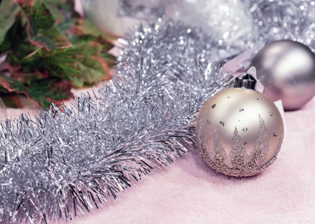 Beige Christmas balls and silvery tinsel on a pink background.の写真素材
