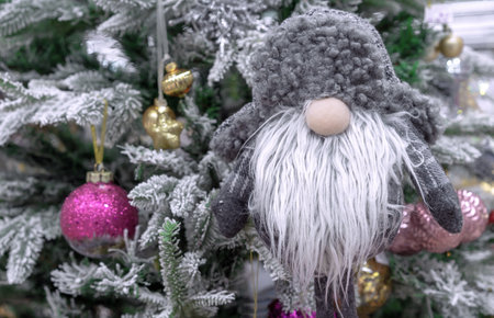 Toy brownie in a gray fur hat near a decorated Christmas tree.の写真素材