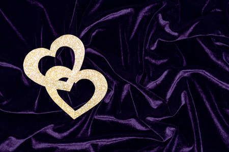 Two shiny gold hearts on a purple velvet background. Valentine's day concept.の写真素材