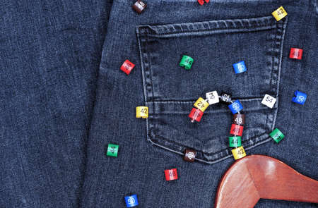 Clothes hangers with multicolored plastic size labels on a denim backdrop.の写真素材
