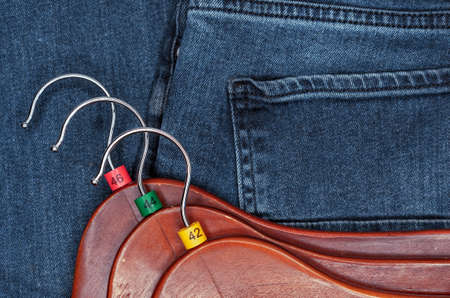 Clothes hangers with multicolored plastic size labels on a denim backdrop.の写真素材