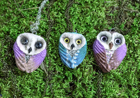 Pendants of an owl with expressive eyes on a green background.の写真素材