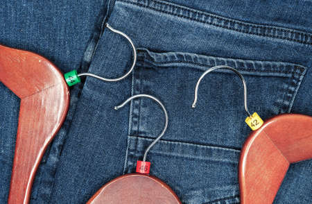 Clothes hangers with multicolored plastic size labels on a denim backdrop.の写真素材