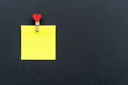 Yellow sticker with a clothespin on a black background.の写真素材