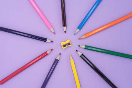 Colored pencils for drawing and a sharpener on a lilac background.の写真素材