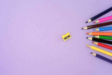 Colored pencils for drawing and a sharpener on a lilac background.の写真素材