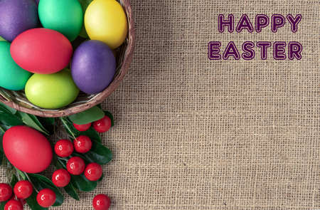 Easter eggs in a wicker basket, red berries and the inscription "Happy Easter".の写真素材