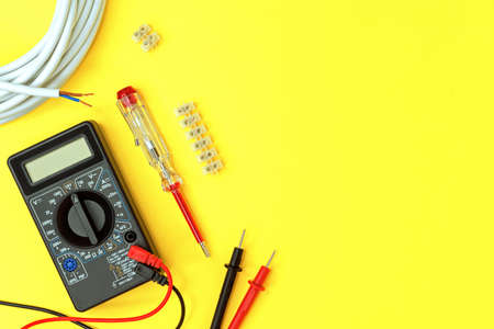 Digital multimeter and indicator screwdriver on a yellow background. Voltmeter, ohmmeter, ammeter.の写真素材