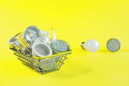 LED energy saving lamps in a metal shopping basket on a yellow background.の写真素材