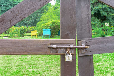 Old metal latch with a lock on the wooden gates of the honey apiary.の写真素材