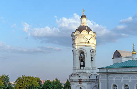 An ancient Russian church with a bell tower in the rays of sunset against a blue sky.の写真素材