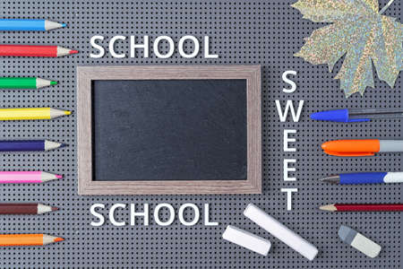 Black chalk board and school supplies on a gray background with the inscription "School sweet school".の写真素材