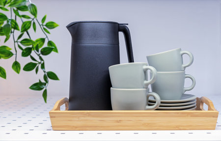 Black teapot and green cups with a saucers on a wooden tray.の写真素材