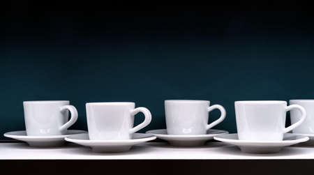 White coffee cups with saucers on a dark green background.の写真素材