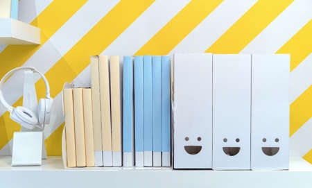 Shelf with books, textbooks, folders and headphones in the children's room.の写真素材