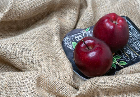 Two red juicy apples on a coarse linen fabric.の写真素材